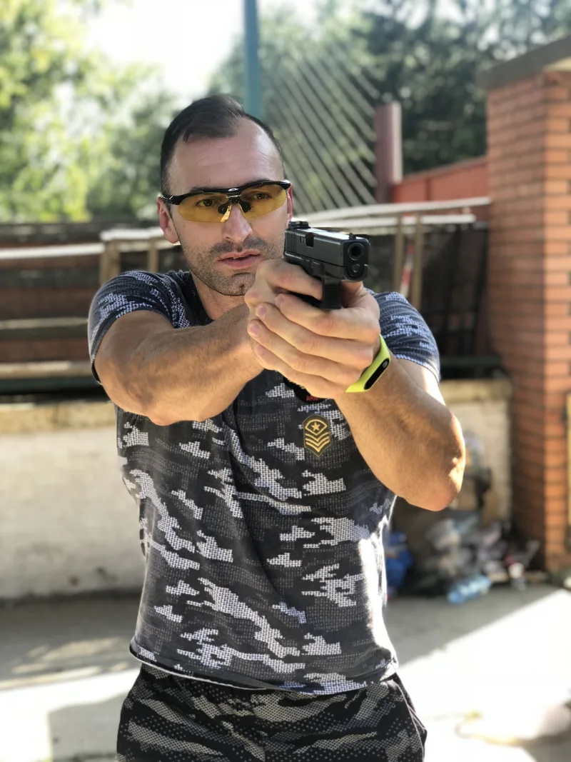 Strelac sa zaštitnim naočarima drži pištolj u dvoručnom stavu