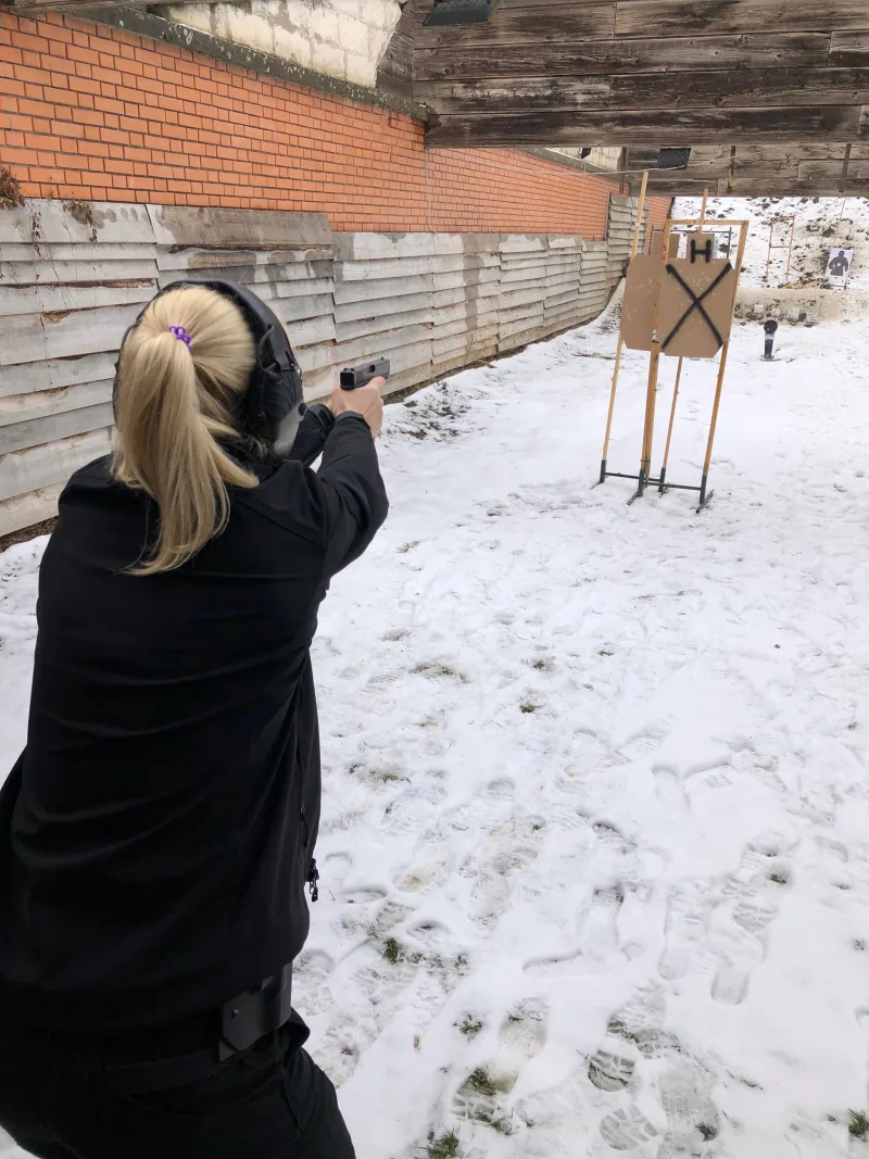 Strelkinja gađa pištoljem ka papirnim metama zimi